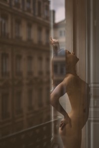 Du glamour, des courbes et une belle lumière séance photo sensuel à Lyon femme nue devant une fenêtre avec les reflets de la ville