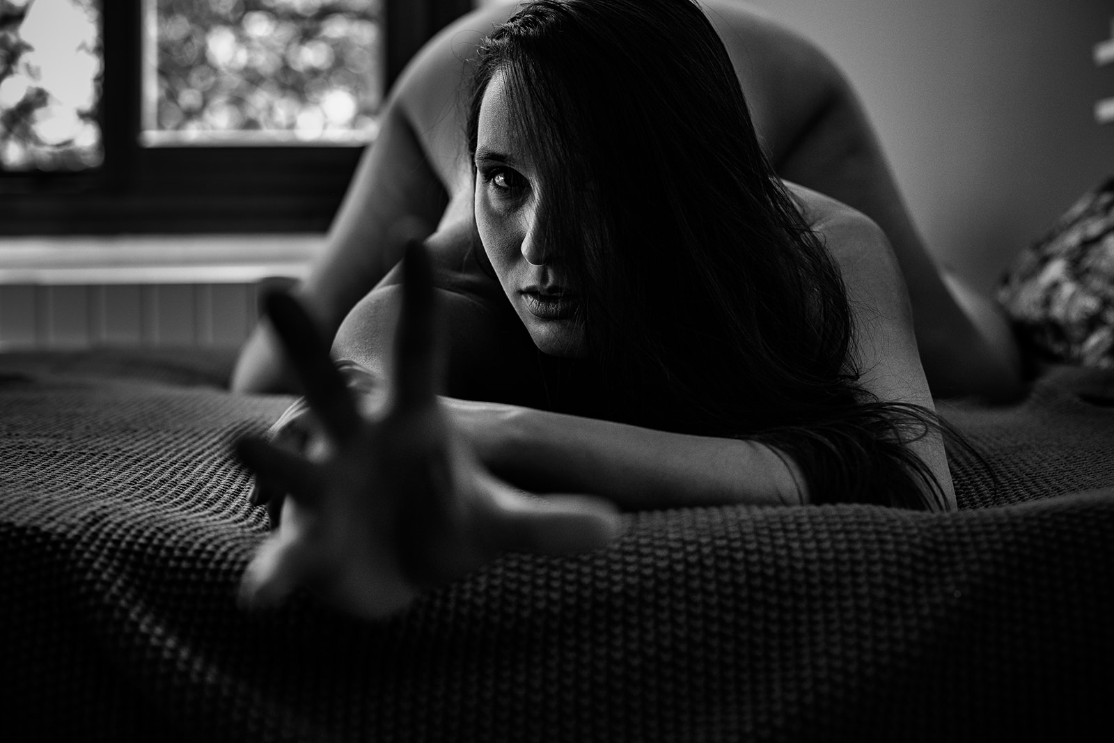 Séance boudoir – désir offert en noir et blanc Femme en séance boudoir noir et blanc, offerte et tendant la main vers l’objectif