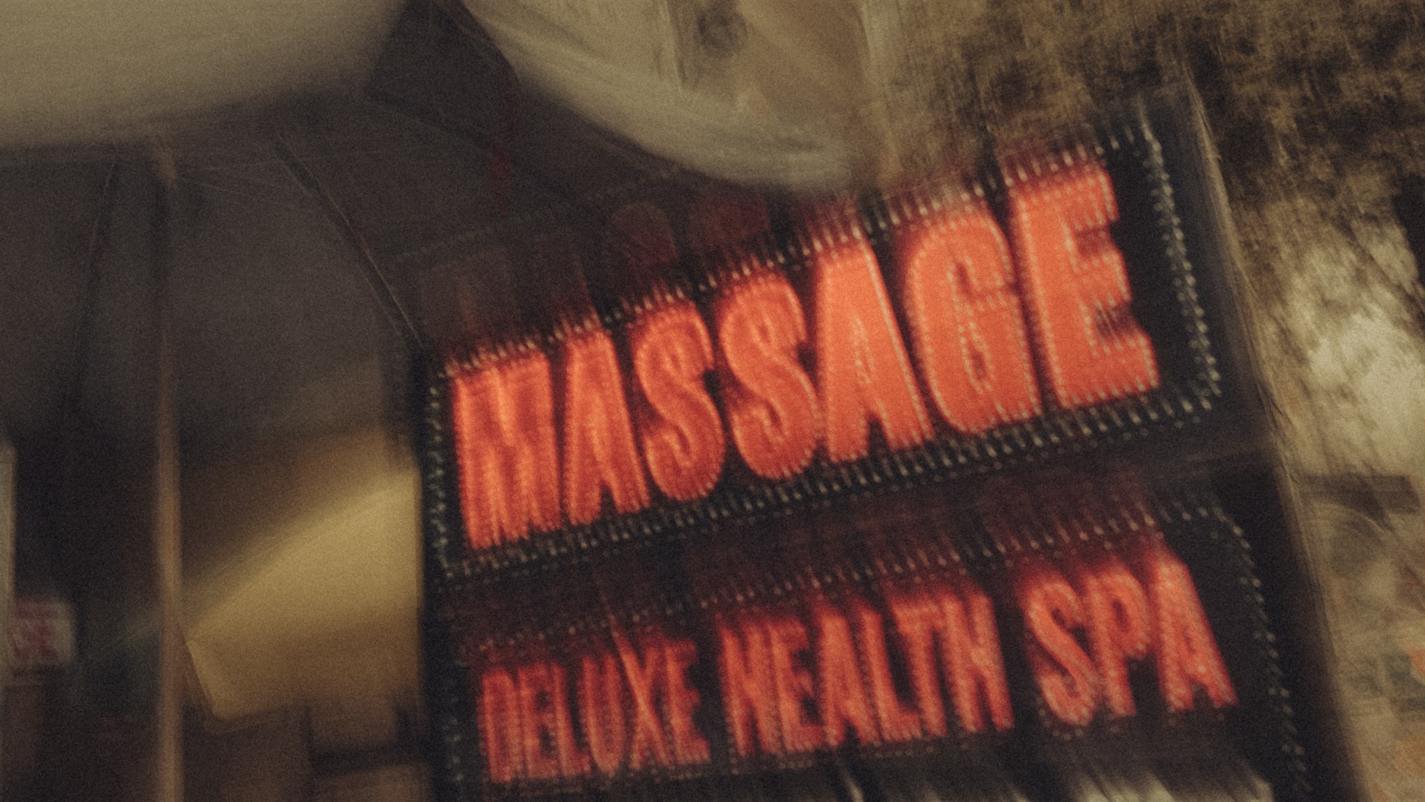 Massage, nuit et ambiguïtés Enseigne de massage nocturne en Thaïlande, floue, évoquant la banalisation du travail du sexe